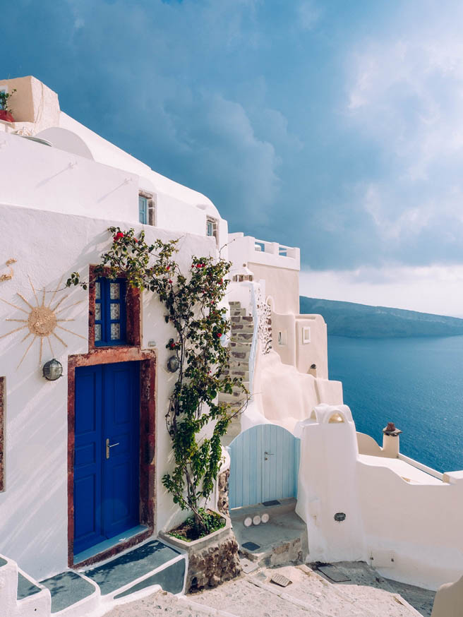 A vertical shot of a building with a blue door at Santorini, Gre